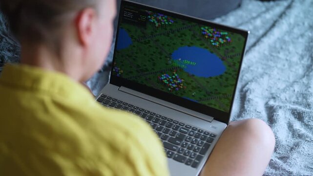 Woman playing economic strategy game on laptop.