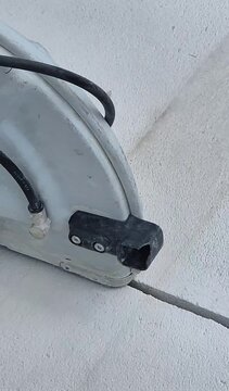 Vertical 9:16 smartphone shot of a large handheld power cutter slicing diagonally through a concrete wall from a top angle view.