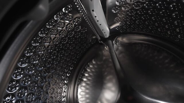Empty stainless steel washing machine drum inside view close up.