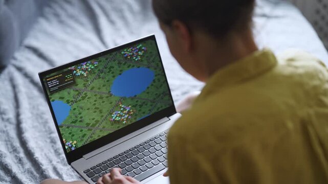 Woman playing economic strategy game on laptop.