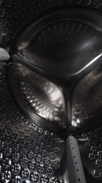 Empty stainless steel washing machine drum inside view close up.