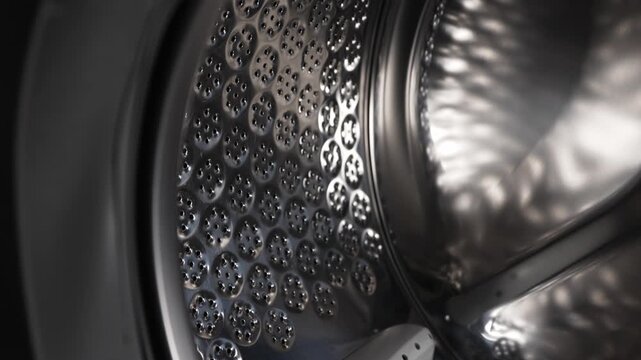 Empty stainless steel washing machine drum inside view close up.