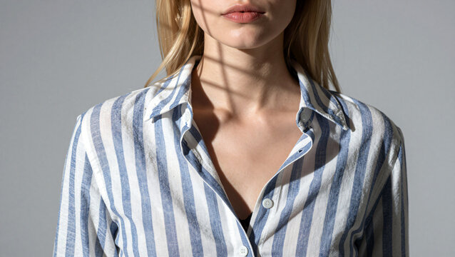 Close up of woman wearing open striped shirt with window shadow