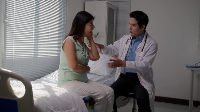 Concerned doctor comforting and explaining health issues to an unhappy mature female patient sitting on a hospital bed while she experiences various pains