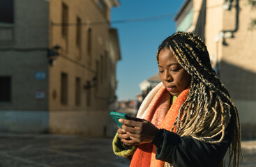 Fototapeta premium Black woman using smartphone on urban street