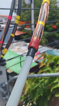Close up video of red mastic sealant tape wrapped on the copper wire screen of a high voltage underground cable termination during electrical infrastructure maintenance.