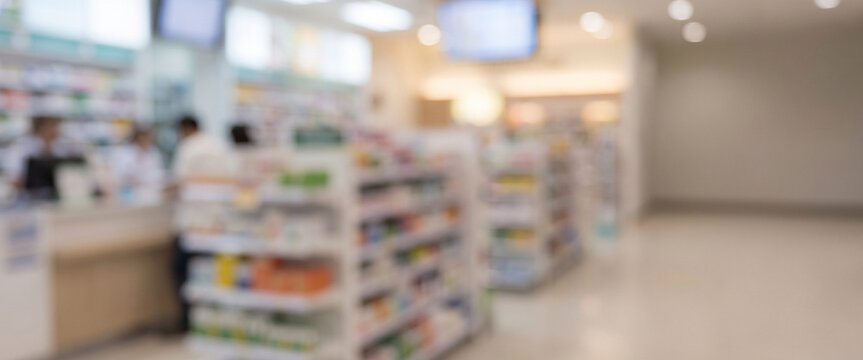 A blurred interior view of a pharmacy, featuring shelves stocked with various health products and a pharmacy counter in the background.