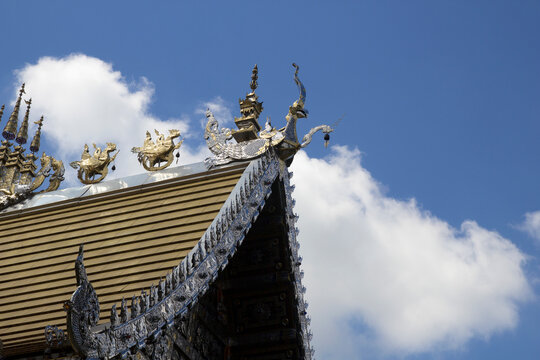 The eaves of a beautifully decorated Thai temple against a backdrop of the sky.