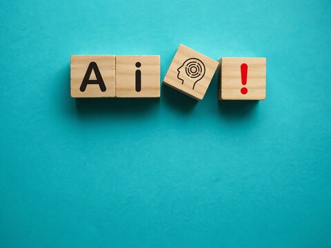 Wooden blocks with AI text and brain icon. Artificial intelligence concept on blue background.