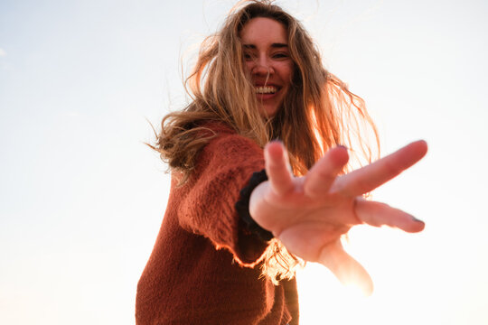 A woman dancing with a smile as the sun sets in an open space