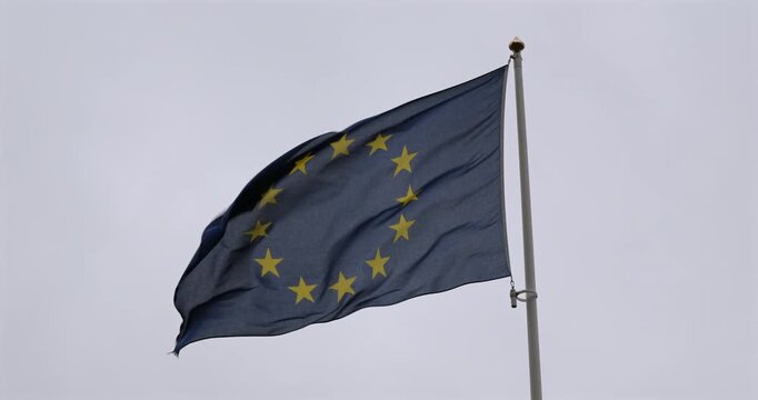 European Union flag waving on a flagpole against an overcast sky