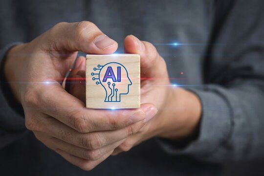 Person holding wooden block with AI icon. Artificial intelligence concept for technology.
