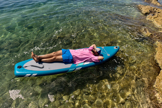 Man Relaxing on Paddle Board in Clear Coastal Water