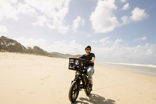 Smiling man riding e bike across wide sandy beach