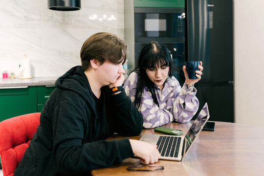 Two women work together at home on a laptop.