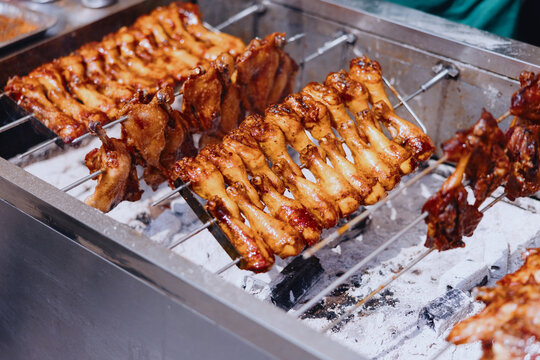 Fresh Chicken Skewers Cook Over Hot Coals in a Busy Street Stall