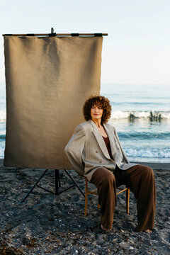Woman with curly hair posing on beach studio set