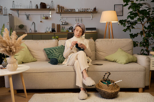 Elegant senior woman enjoying her time knitting in a cozy modern apartment