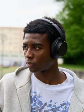 Young Man Listens to Music With Headphones in a Park Setting