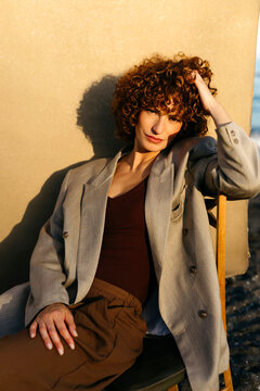 Woman with curly hair posing in blazer at golden hour
