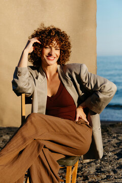 Woman with curly hair smiling sitting on beach chair