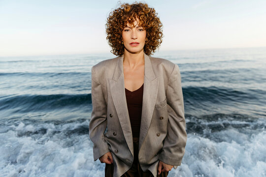 Woman standing on beach with waves washing ashore