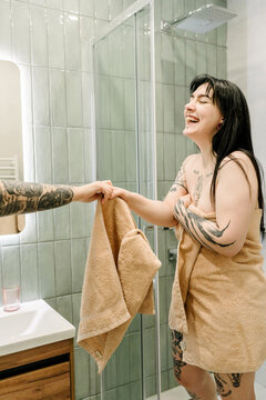 Two friends exchange towels in the bathroom.