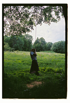 A woman gazes up at an ancient tree in a summer forest
