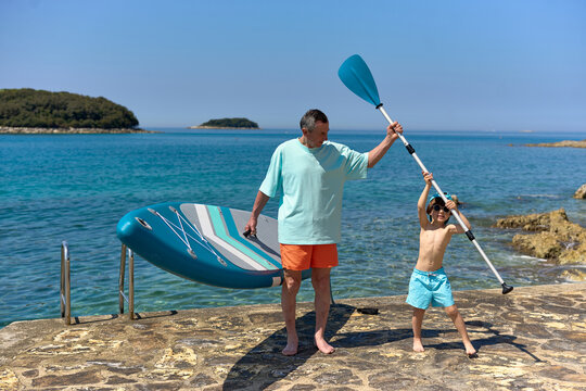 Grandfather and Grandson Preparing for Paddle Boarding Adventure