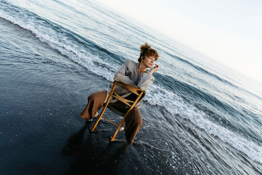 Woman sitting on chair in ocean waves contemplating nature