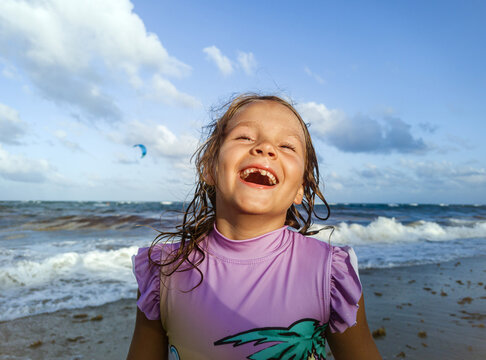 Happy child portrait in ocean waves on sunset beach