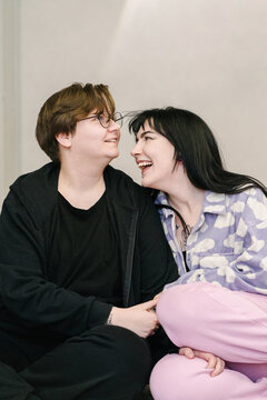 Two friends are laughing, sitting next to each other.