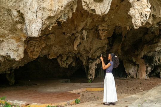Woman photographing Taino petroglyphs in cave