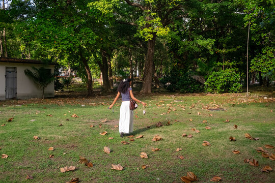Woman walking through leafy tropical park
