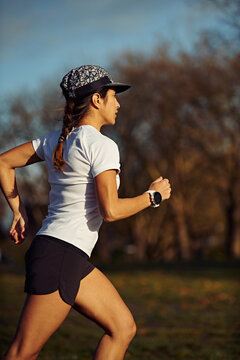 Athletic Woman Jogging Through Park At Sunset