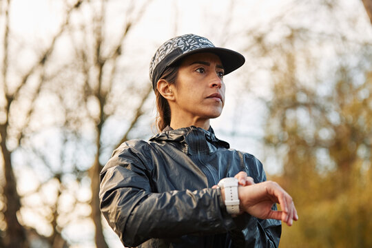 Female Runner Timing Workout In Evening Light
