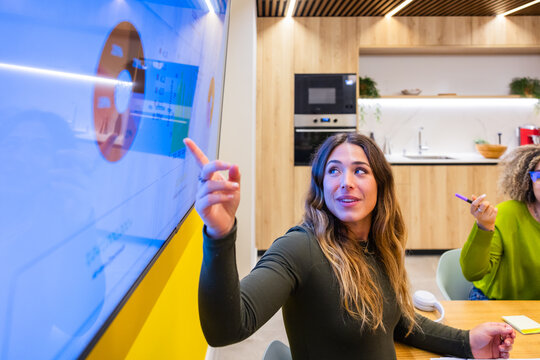 Woman presenting data on a screen during a meeting