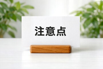 Obraz premium 「注意点」と書かれた白いカードが木製スタンドに立つビジネスシーン