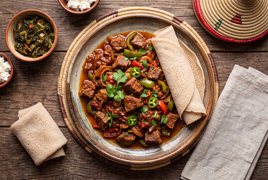 Traditional Ethiopian beef tibs served with spongy injera flatbread and spicy vegetable sauce.