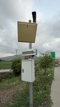 Security camera pole with sensor panel, weight screen, and power box at Chakdara toll gate.