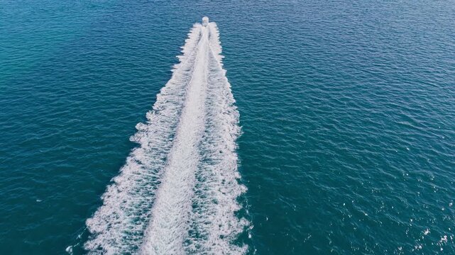 Luxury yacht glides across blue sea beneath bright sky. Boat leaves marina with motorboat behind. Summer vacation continues. Sea offers endless freedom