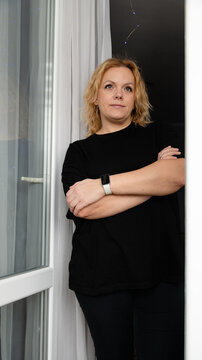 Woman standing in doorway with arms crossed and looking away during evening