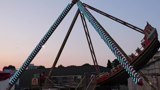 Pirate ship pendulum ride swinging at sunset amusement park