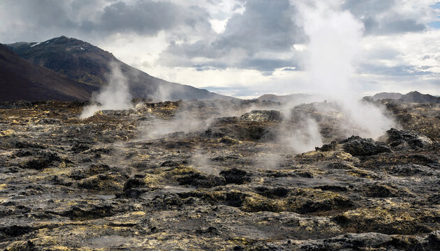 Geothermal volcanic landscape with rising steam vents and dark rocky ground under a dramatic cloudy sky in a remote wilderness area