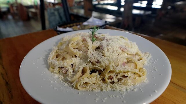 plate of delicious fettuccine pasta with parmesan cheese on wooden table