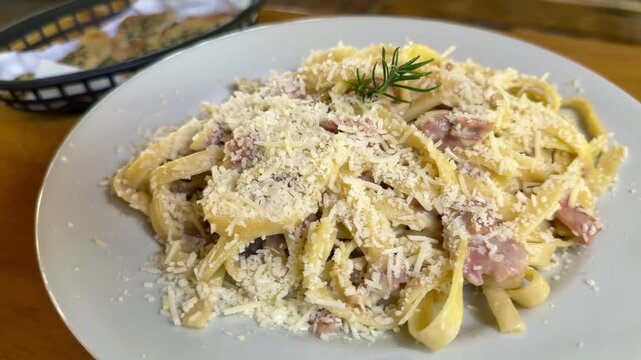 plate of delicious fettuccine pasta with bacon and grated cheese