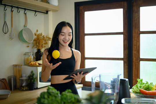 Young Woman in Sportswear Using Tablet While Preparing Healthy Meal in Modern Kitchen