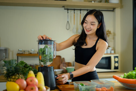Young Woman Preparing Kale Green Smoothie in Blender at Home Kitchen for Healthy Wellness Lifestyle