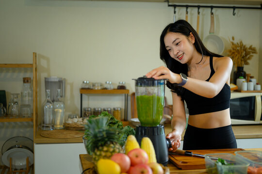Young Woman in Sportswear Blending Kale Green Smoothie in Home Kitchen for Healthy Lifestyle