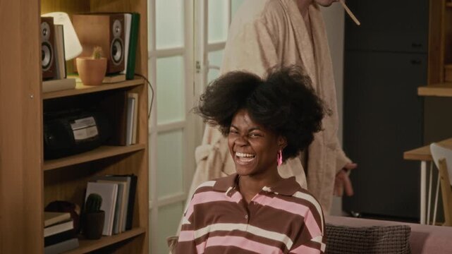 Diverse young friends hanging out in apartment, Caucasian man brushing teeth while friend shows vintage camera. Perfect for youth lifestyle or roommate housing advertisements